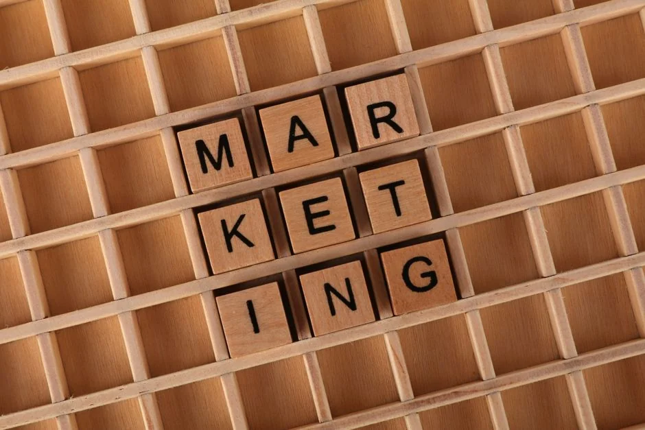 A contemporary work setting where hands review marketing data on a laptop and printed documents.